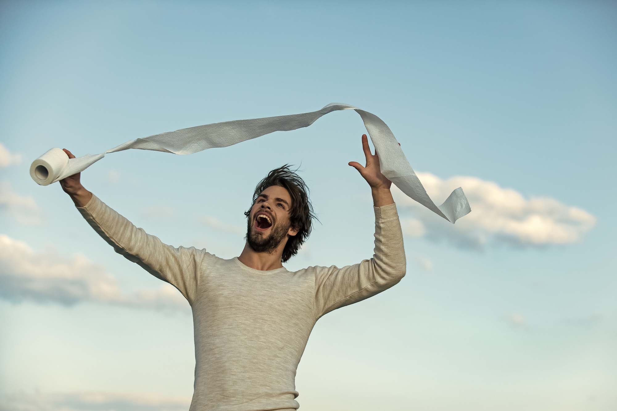 A guy holding a toilet roll happily